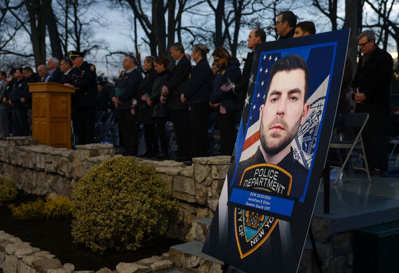 © Reuters. A portrait of late NYPD Officer Jonathan Diller, who was shot and killed while making a routine traffic stop on March 25th in the Far Rockaway section of Queens, is pictured during a candlelight vigil at Brady Park in Massapequa, New York, U.S., March 27, 2024. REUTERS/Shannon Stapleton