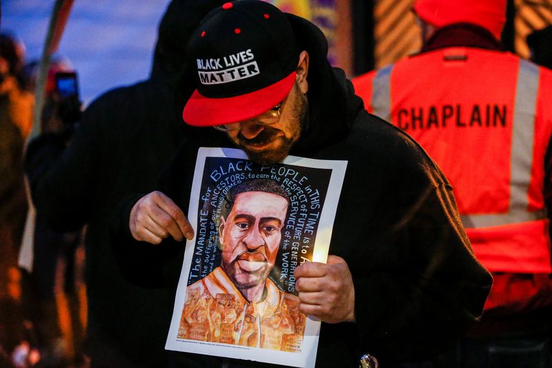 © Reuters. FILE PHOTO: A man holds an image of George Floyd at a vigil on the second anniversary of the death of Floyd, a black man who was killed in 2020 by white police officer Derek Chauvin by kneeling on his neck, in Minneapolis, Minnesota, U.S. May 25, 2022. REUTERS/Eric Miller/File Photo